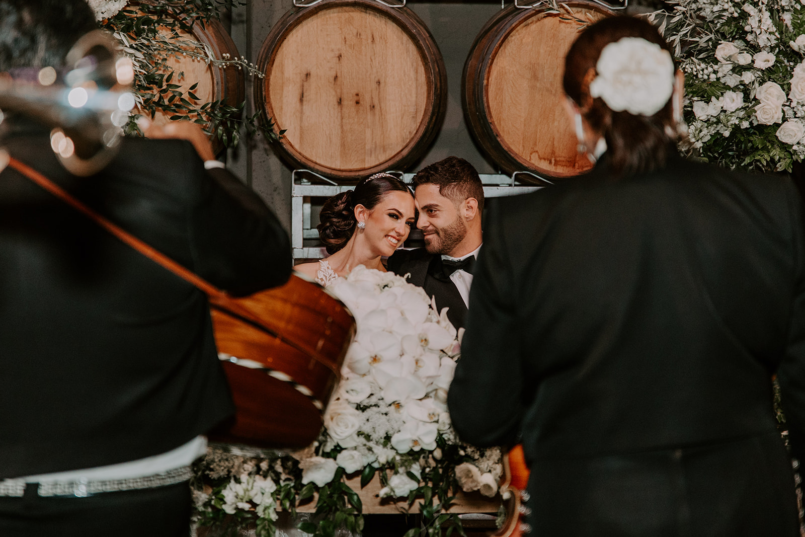 A couple celebrating their wedding at Domenico Winery San Carlos in front of the cask wall with a mariachi band playing