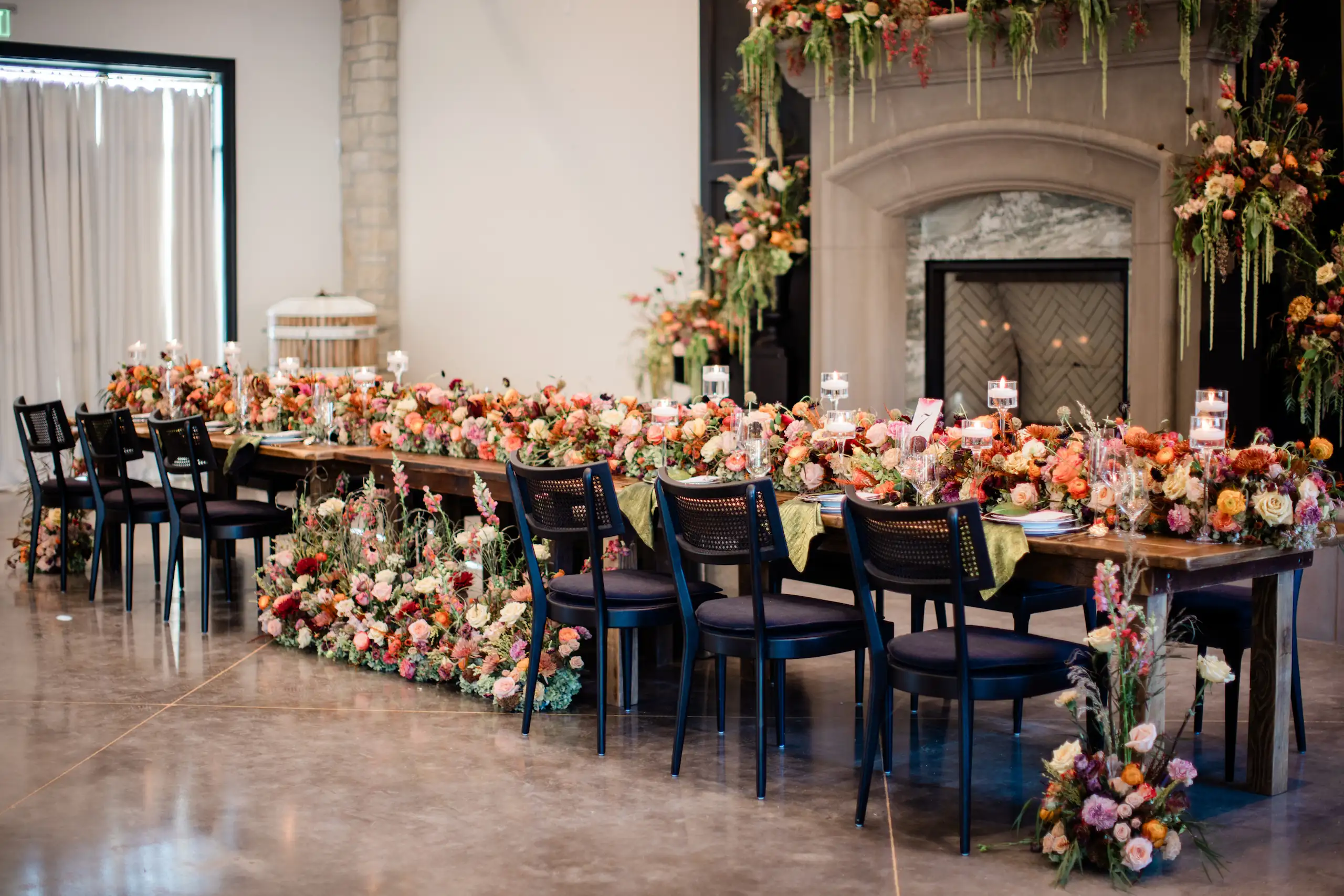 A large event table setup with flower in fron of the Domenico Amador fireplace hosting weddings