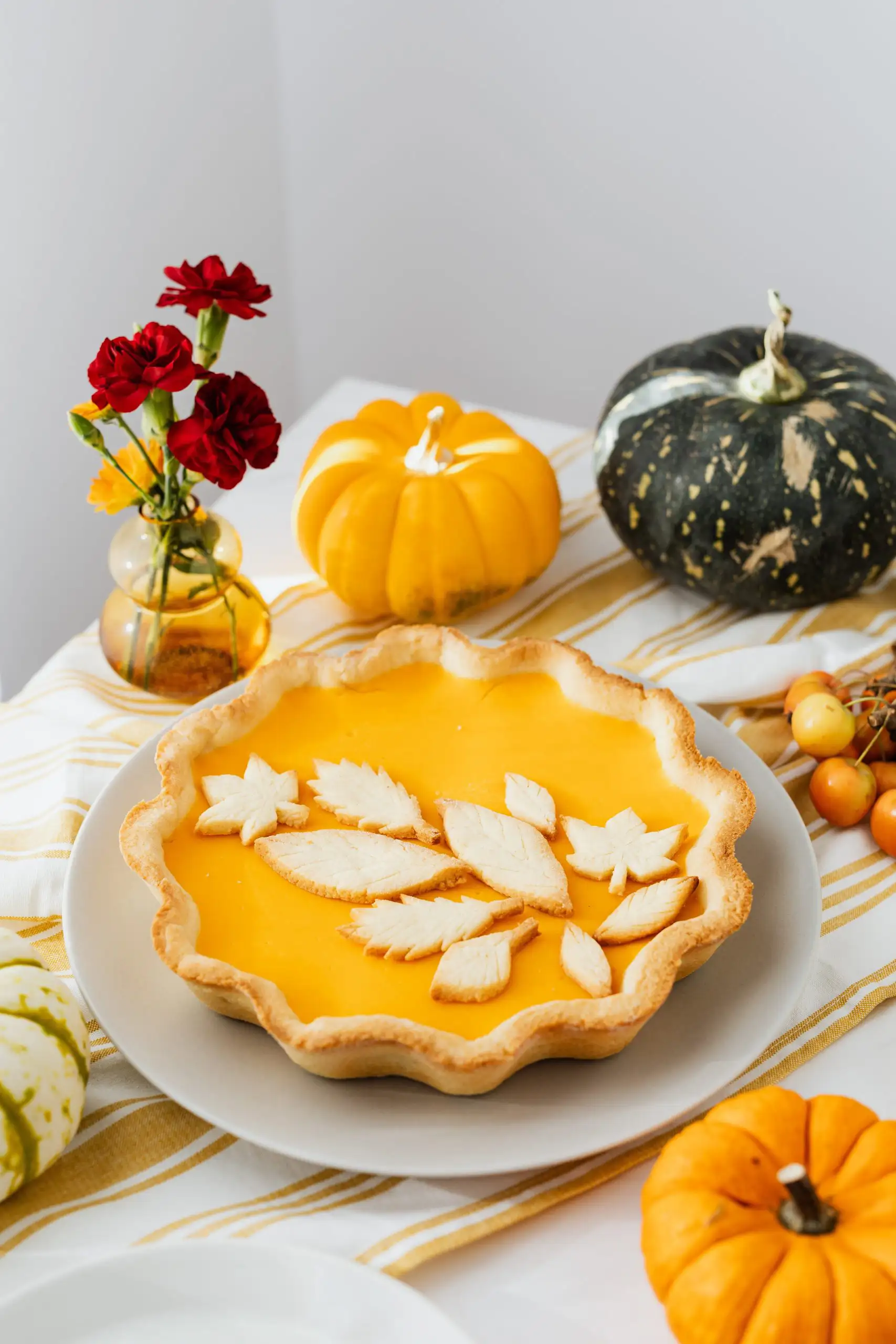 Wine and Pie Pairings that Will Change Your Life | Domenico Winery A beautifully arranged pumpkin pie with a decorative leaf-shaped crust, set against autumn-themed decor.