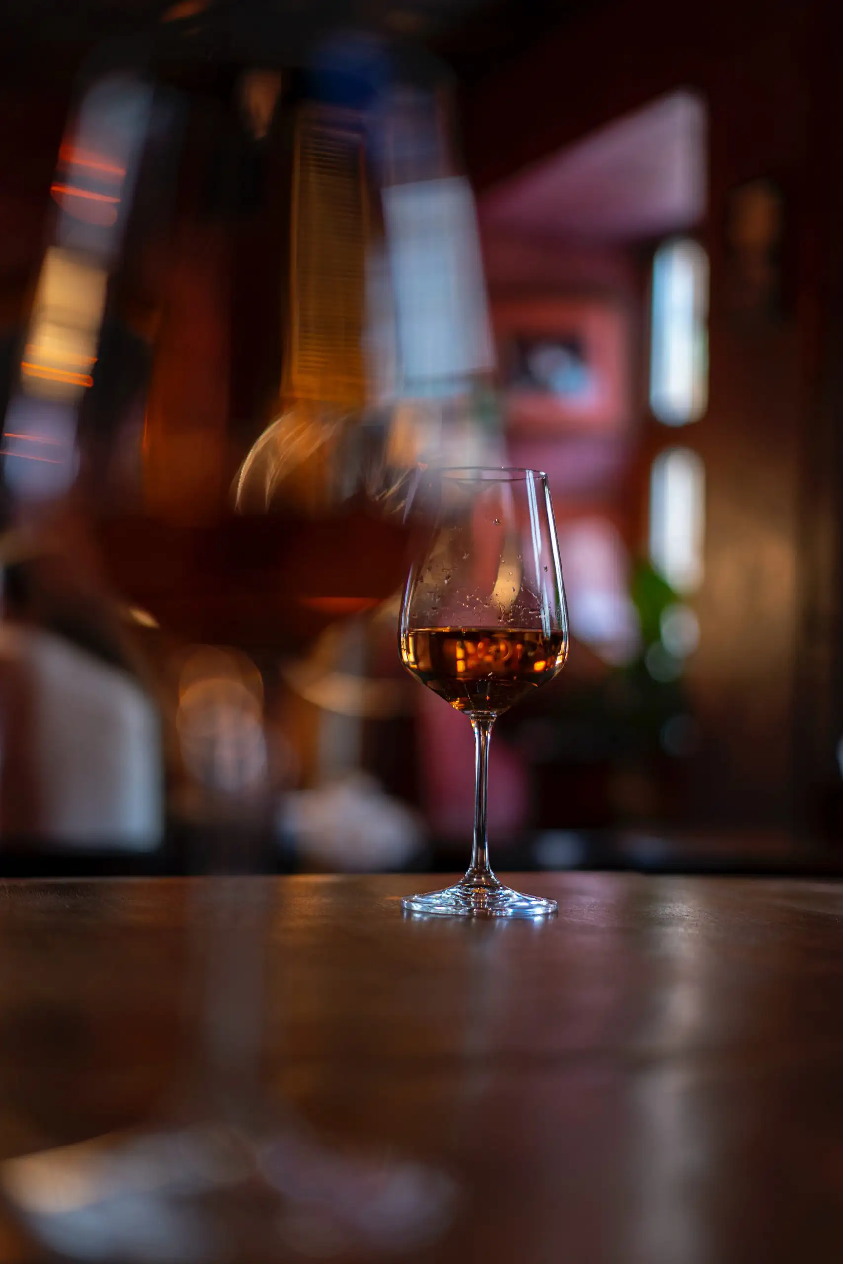 A close-up of a glass of wine with a blurred foreground, creating a cozy and elegant restaurant atmosphere.