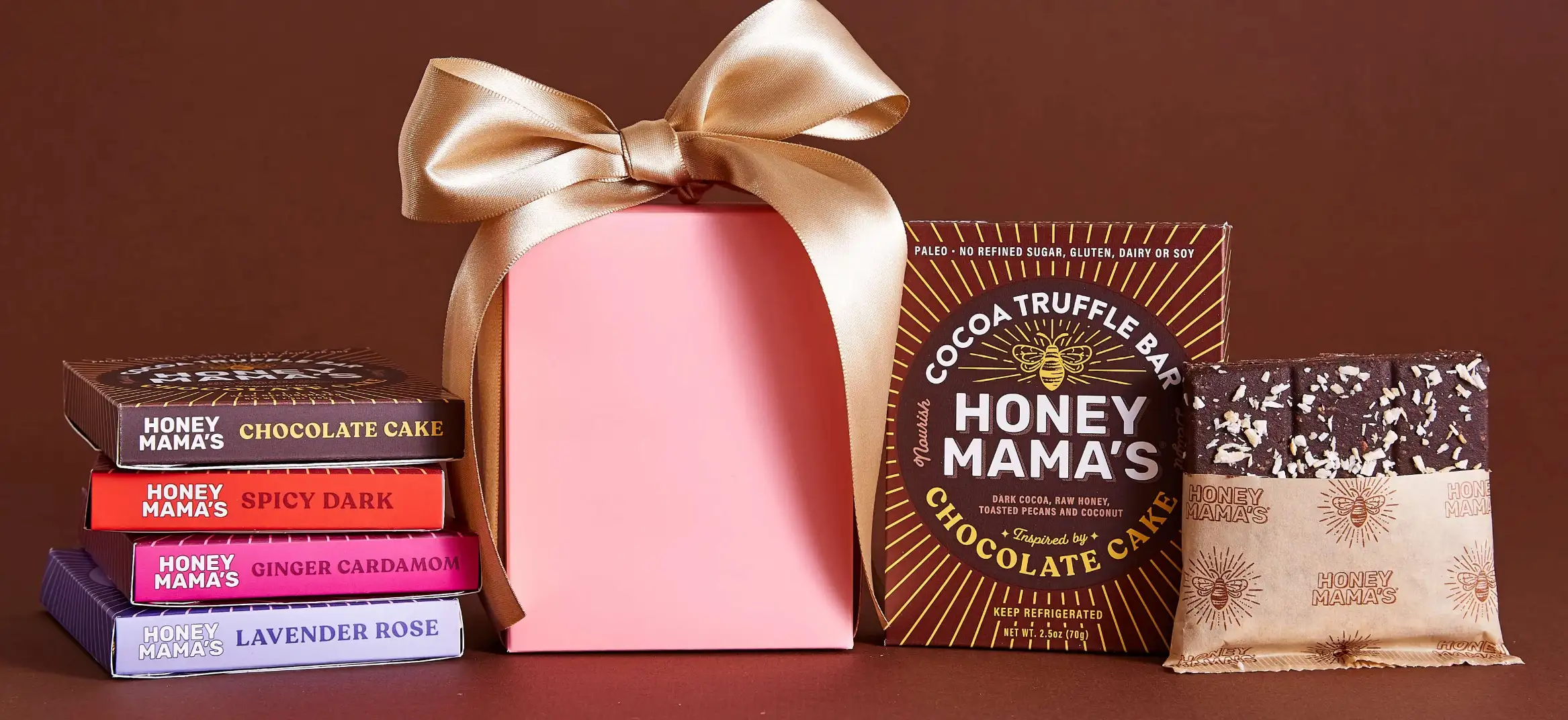 Don't Miss These Wine and Dessert Pairings | Domenico Winery A collection of Honey Mama's cocoa truffle bars in various flavors like Lavender Rose and Spicy Dark, next to a pink gift box with a gold ribbon.