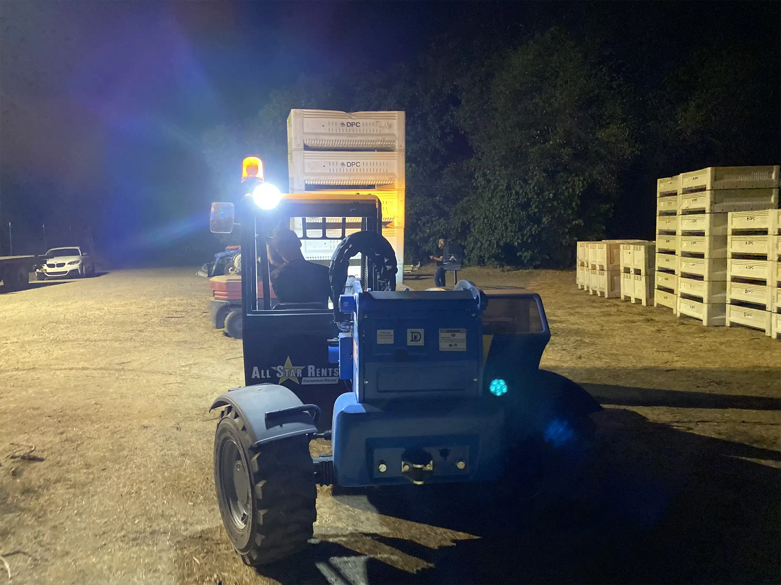 A Quick Guide to a California Wine Harvest | Domenico Winery A forklift operating at night in a vineyard, moving stacks of white grape harvest bins under bright work lights.