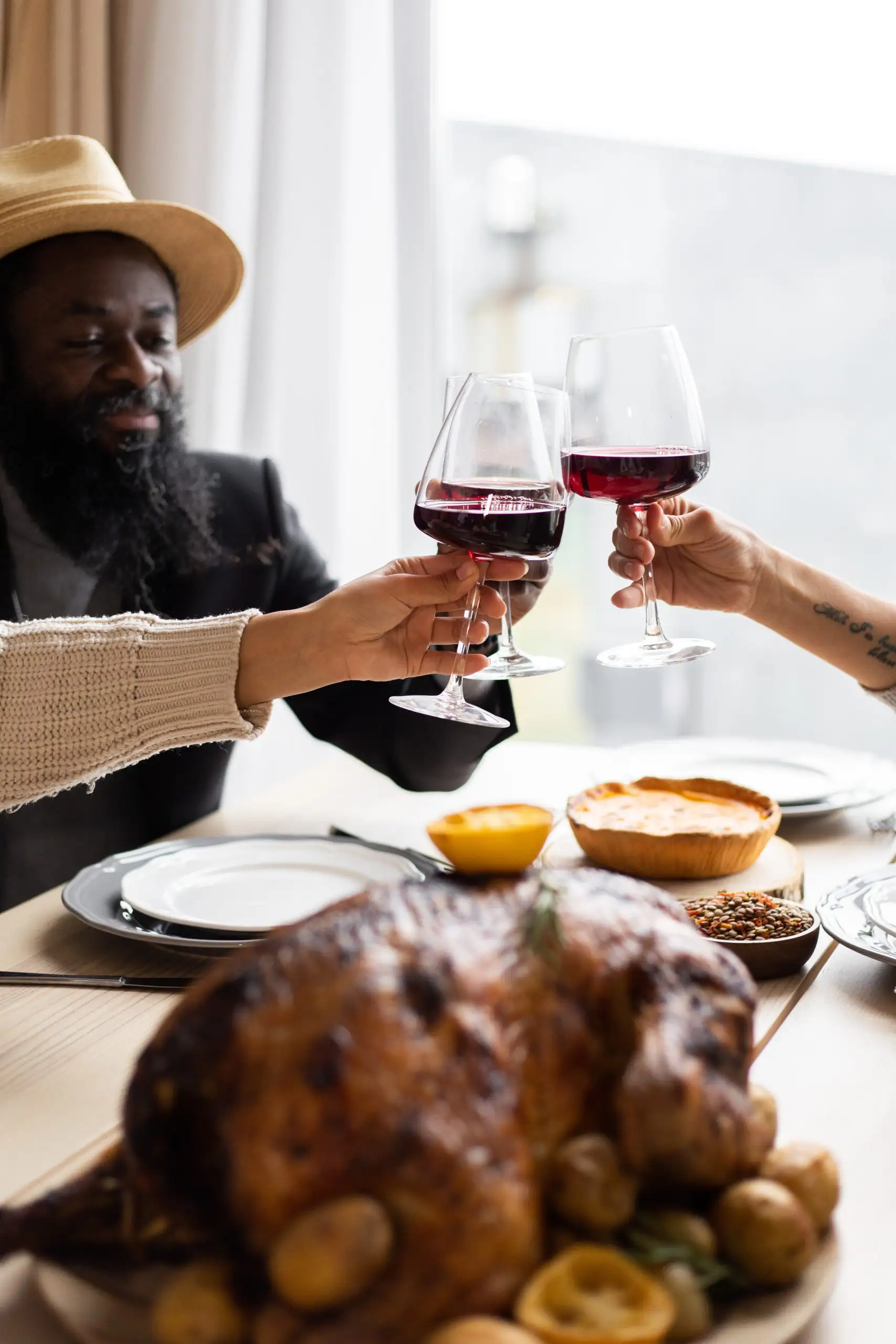 5 Best Holiday Wines You Must Try | Domenico Winery People toasting with glasses of red wine during a festive dinner with roast turkey and side dishes.