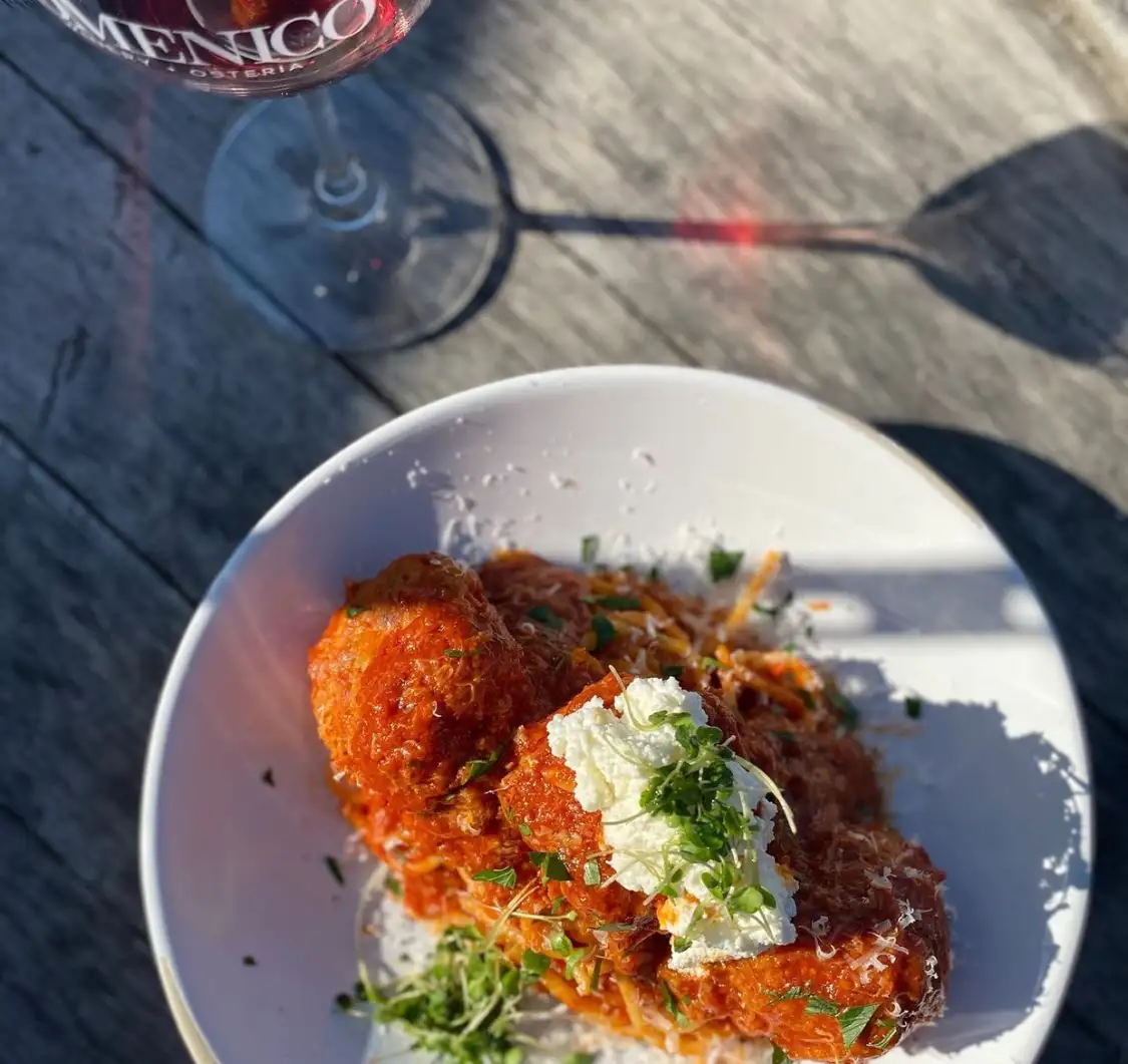 Italian Food 101: Pairing Wine with Pasta | Domenico Winery Bowl of spaghetti and meatballs with tomato sauce, ricotta cheese, and herbs on an outdoor table with a glass of red wine