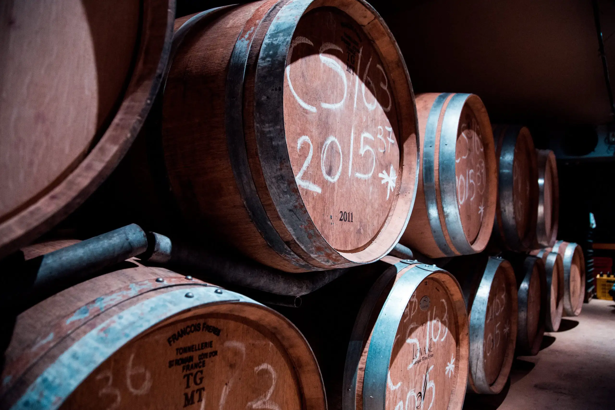 What Happens in a Winery During the Winter? | Domenico Winery Wine barrels stacked in a dimly lit cellar with vintage markings